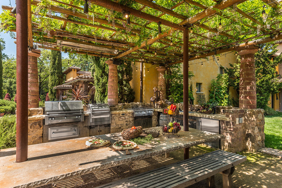 This is an example of a mid-sized country backyard patio in San Francisco with an outdoor kitchen, gravel and a pergola.
