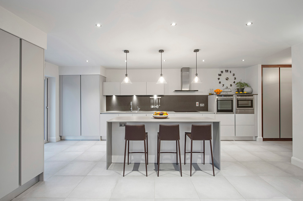 Large contemporary single-wall eat-in kitchen in Dublin with an integrated sink, flat-panel cabinets, white cabinets, marble benchtops, metallic splashback, metal splashback, panelled appliances, ceramic floors and a peninsula.