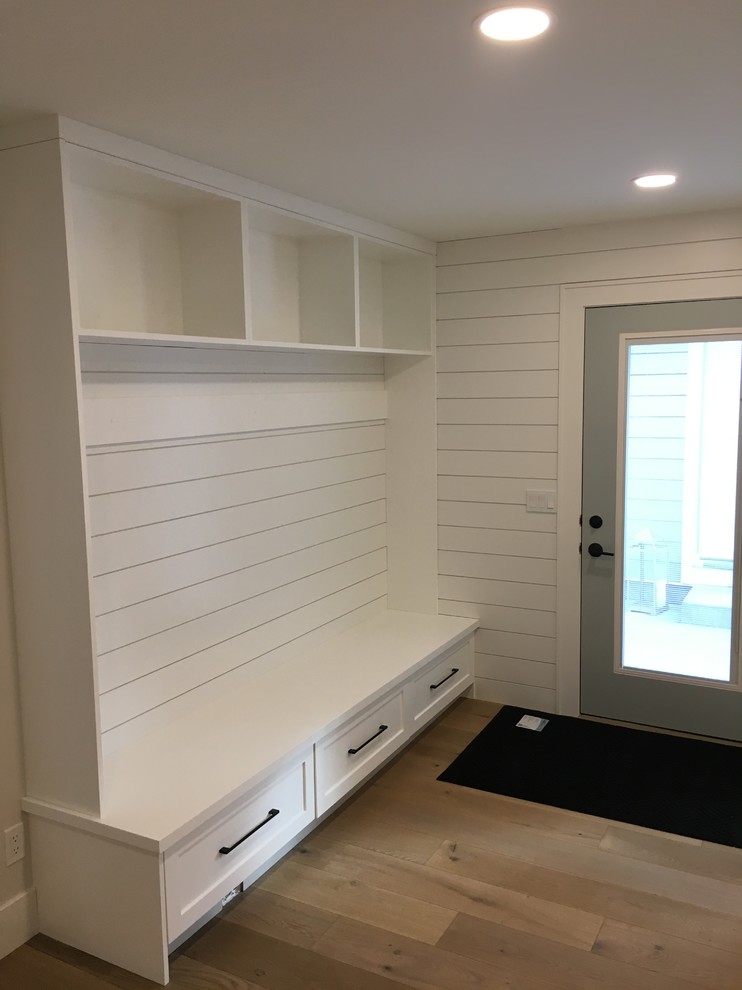 Photo of a contemporary mudroom in Calgary with white walls, medium hardwood floors, a single front door, a green front door and brown floor.