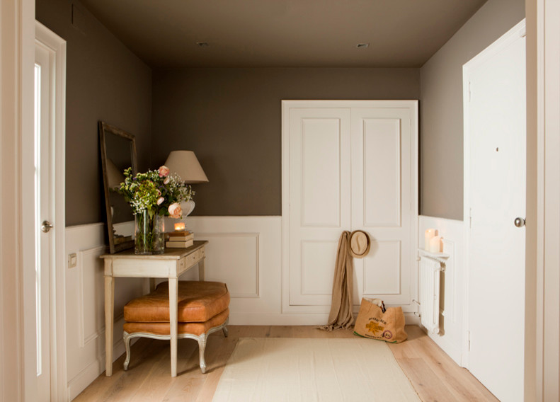 Imagen de distribuidor clásico renovado de tamaño medio con paredes marrones, suelo de madera clara, puerta simple y puerta blanca