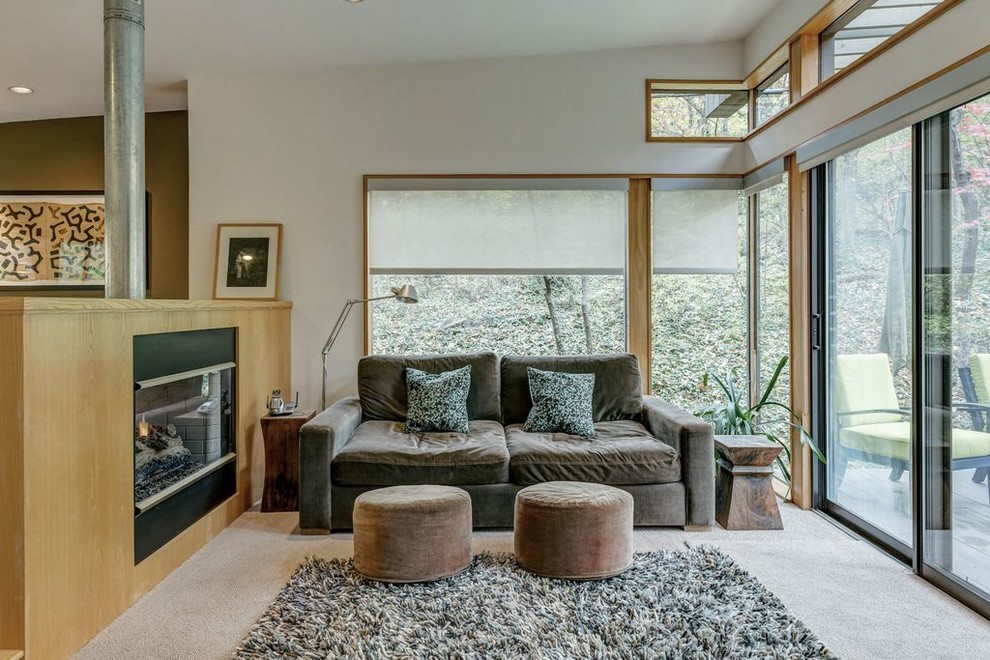 This is an example of a small midcentury master bedroom in St Louis with white walls, carpet, a two-sided fireplace, a wood fireplace surround and beige floor.