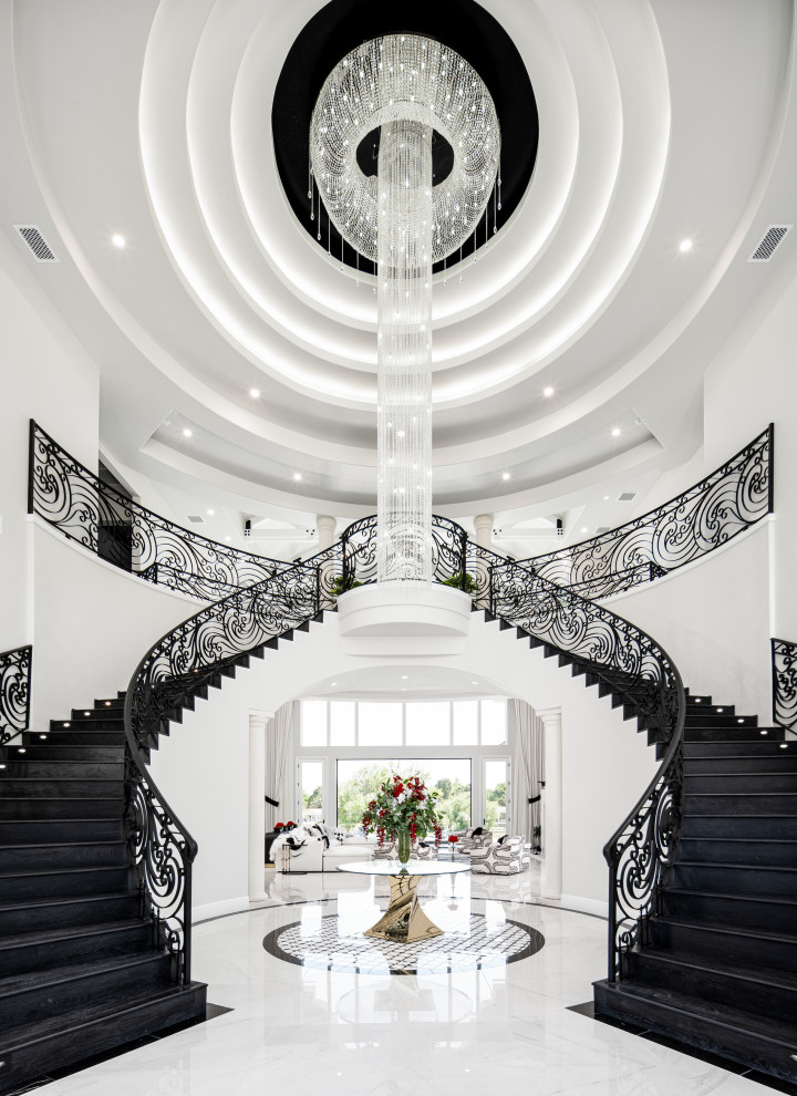 Cette image montre un très grand escalier minimaliste en U avec un garde-corps en métal, des marches en bois, des contremarches en marbre et du lambris.