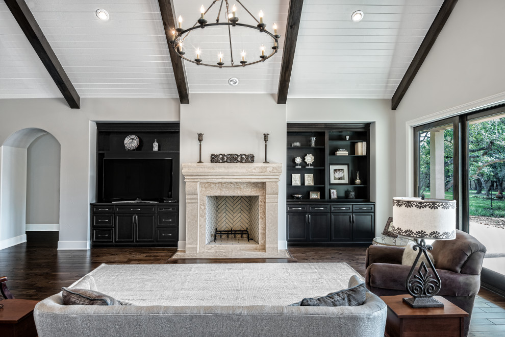 Inspiration for an expansive transitional open concept family room in Austin with grey walls, medium hardwood floors, a standard fireplace, a stone fireplace surround, a built-in media wall, brown floor and exposed beam.
