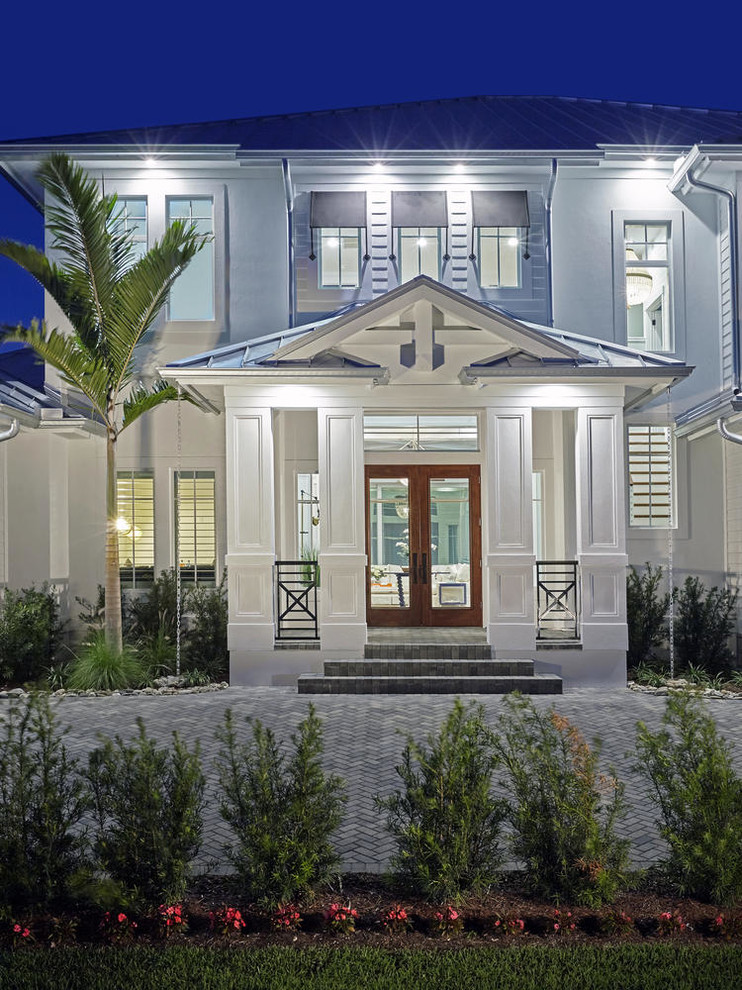 This is an example of a large beach style two-storey white house exterior in Miami with concrete fiberboard siding, a hip roof and a metal roof.