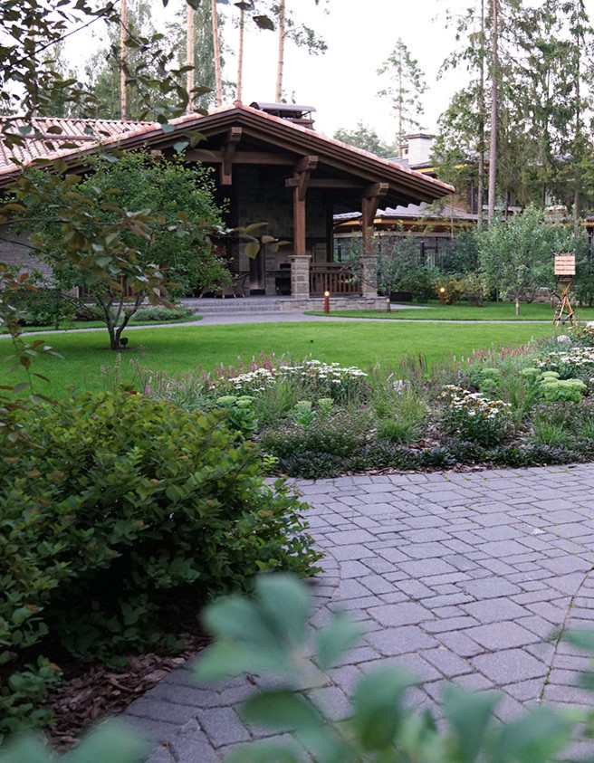 Design ideas for a mid-sized country backyard full sun xeriscape for summer in Moscow with natural stone pavers and a retaining wall.