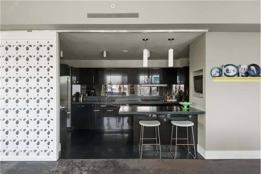 Large contemporary single-wall open plan kitchen in New York with flat-panel cabinets, black cabinets, concrete benchtops, metallic splashback, stainless steel appliances, cork floors and with island.