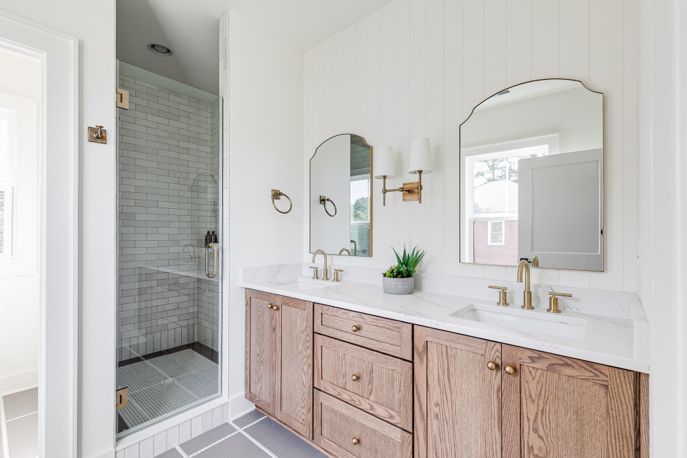 Alcove shower - cottage gray tile gray floor and double-sink alcove shower idea in Richmond with shaker cabinets, light wood cabinets, white walls, an undermount sink, a hinged shower door, white countertops and a built-in vanity