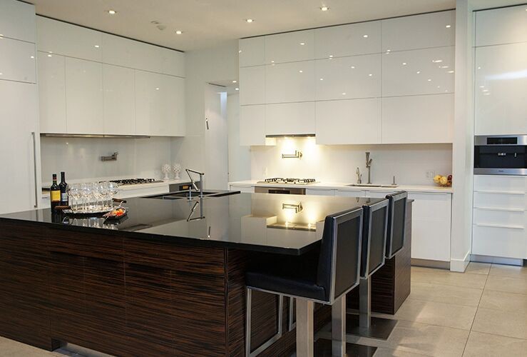 This is an example of a large modern l-shaped eat-in kitchen in Toronto with a double-bowl sink, flat-panel cabinets, white cabinets, solid surface benchtops, white splashback, stone slab splashback, stainless steel appliances, limestone floors and with island.