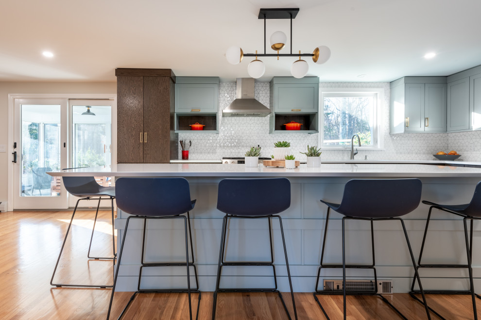 Mid-sized transitional l-shaped kitchen in Providence with an undermount sink, recessed-panel cabinets, grey cabinets, white splashback, ceramic splashback, stainless steel appliances, light hardwood floors, with island, brown floor, white benchtop and quartz benchtops.