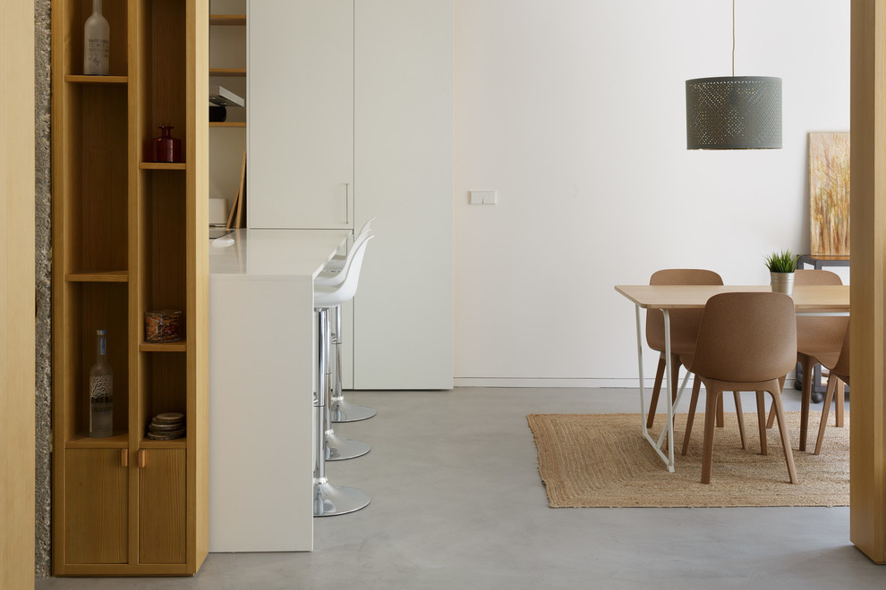 Ejemplo de comedor de cocina contemporáneo pequeño con paredes blancas, suelo de cemento y suelo gris