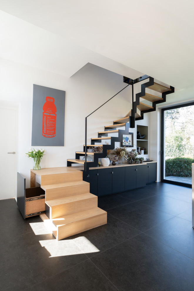 Cette photo montre un grand escalier sans contremarche courbe moderne avec des marches en bois, un garde-corps en métal et rangements.