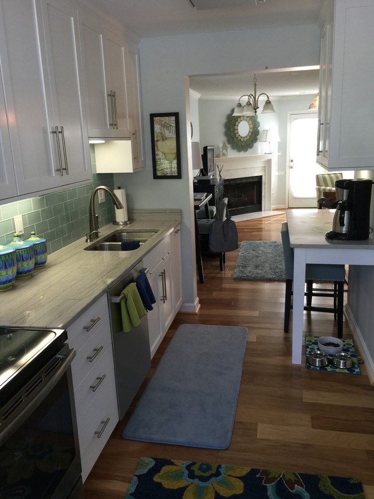 Kitchen - medium tone wood floor kitchen idea with a double-bowl sink, flat-panel cabinets, white cabinets, quartzite countertops, blue backsplash, glass tile backsplash and stainless steel appliances