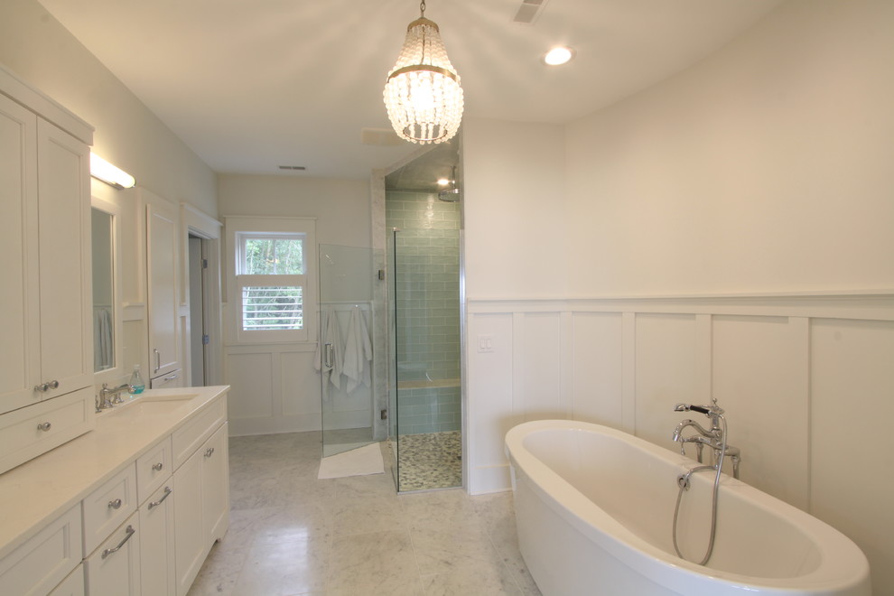 Photo of a mid-sized transitional master bathroom in Grand Rapids with shaker cabinets, white cabinets, a freestanding tub, an alcove shower, a two-piece toilet, beige tile, porcelain tile, white walls, ceramic floors, an undermount sink, engineered quartz benchtops, beige floor and a hinged shower door.