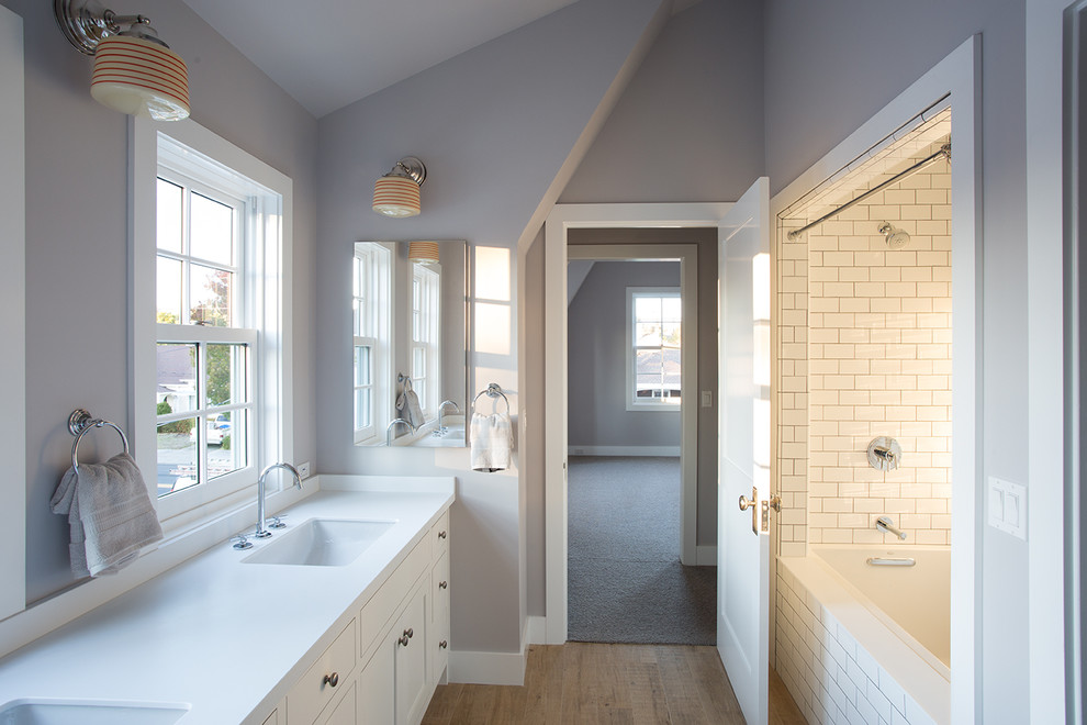 Design ideas for a mid-sized country bathroom in San Francisco with shaker cabinets, white cabinets, an alcove tub, white tile, cement tile, grey walls, porcelain floors, an undermount sink, solid surface benchtops and a shower/bathtub combo.