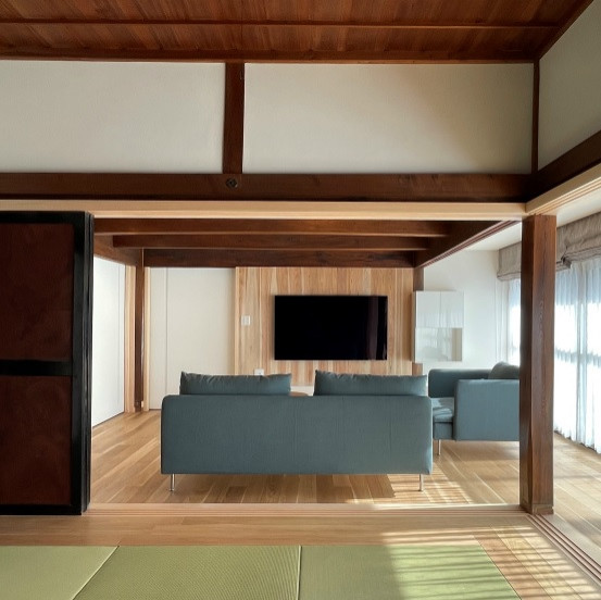 Стильный дизайн: открытая гостиная комната среднего размера в восточном стиле с белыми стенами, полом из фанеры, телевизором на стене и деревянным потолком - последний тренд