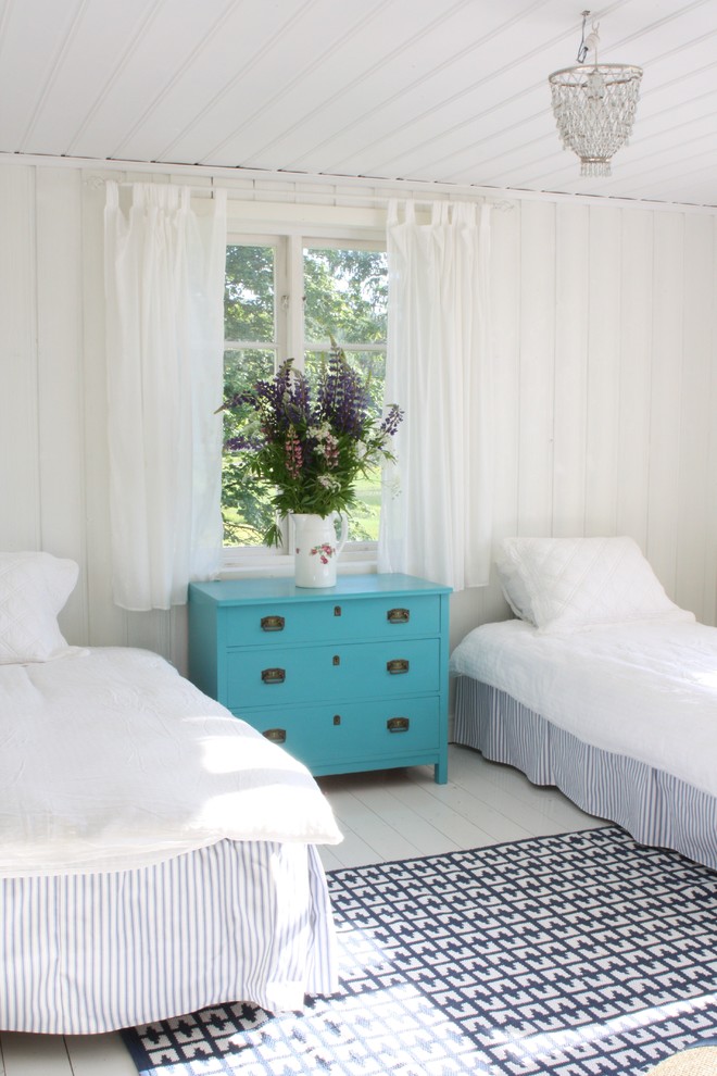 Photo of a country guest bedroom in Los Angeles with white walls, painted wood floors and white floor.