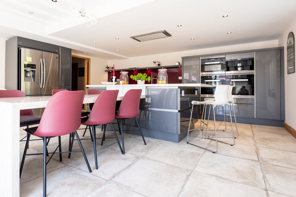 Photo of a large contemporary kitchen in Wiltshire with flat-panel cabinets, grey cabinets, solid surface benchtops, pink splashback, glass sheet splashback, with island and beige benchtop.