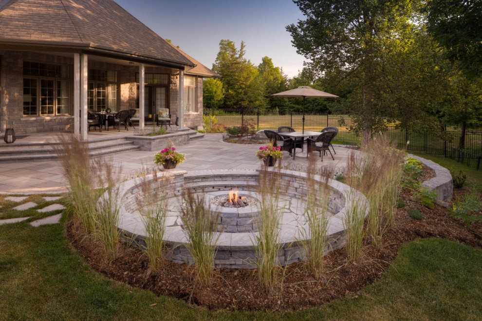 Example of a mid-sized transitional backyard stone patio design in Toronto with a fire pit and a roof extension