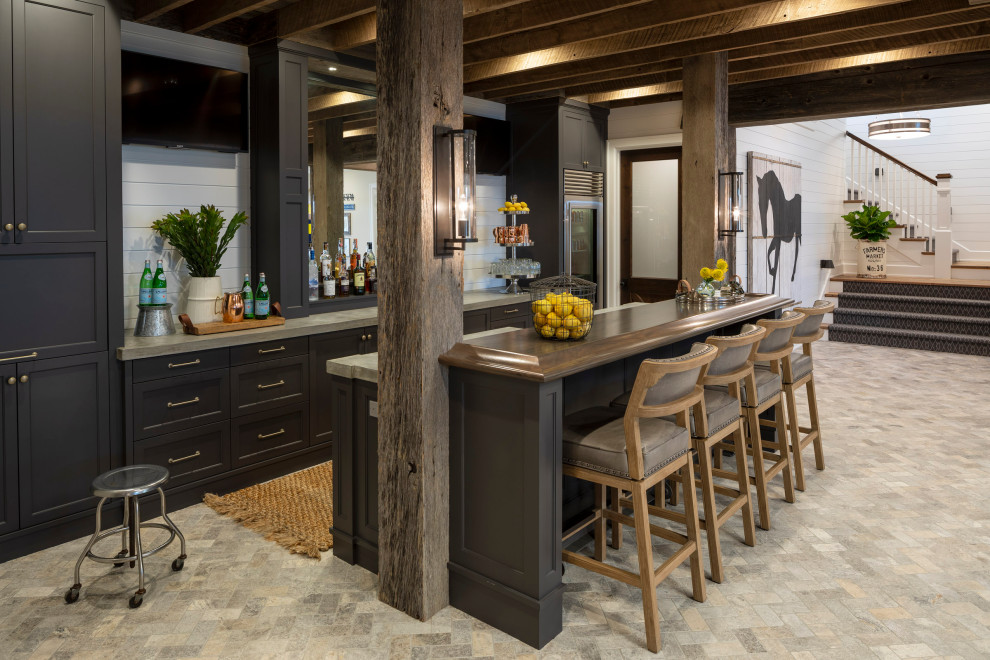 Photo of a large country galley seated home bar in Minneapolis with shaker cabinets, grey cabinets, concrete benchtops, limestone floors, grey floor and grey benchtop.