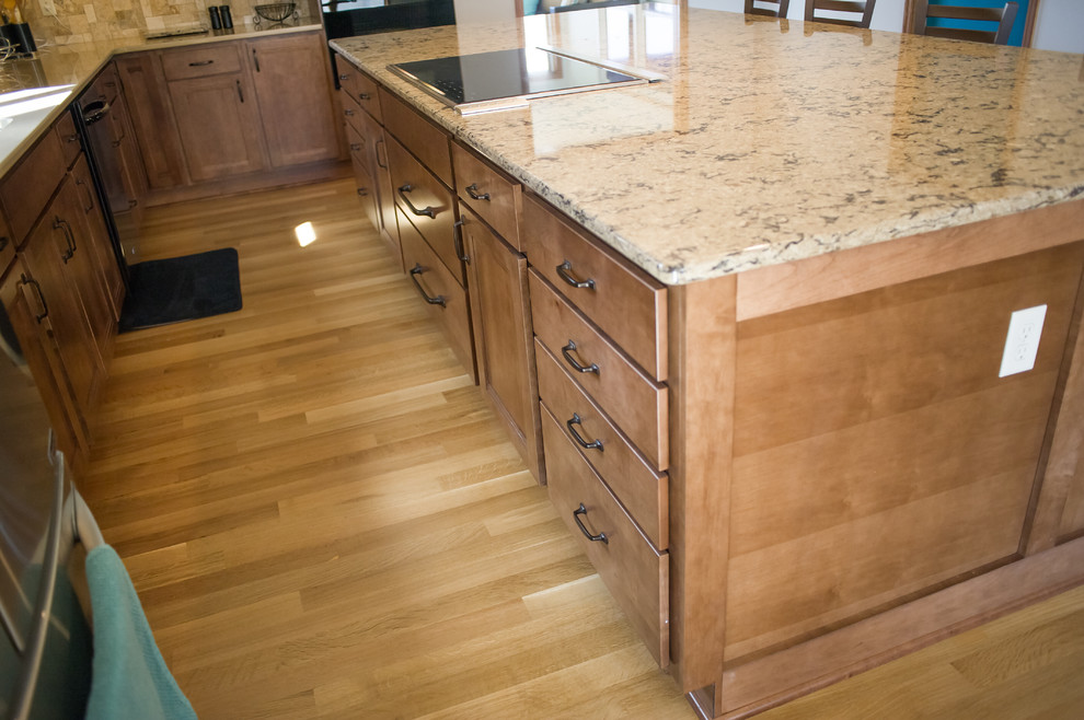 Open concept kitchen - large transitional l-shaped light wood floor open concept kitchen idea with an undermount sink, recessed-panel cabinets, medium tone wood cabinets, quartz countertops, beige backsplash, black appliances and an island