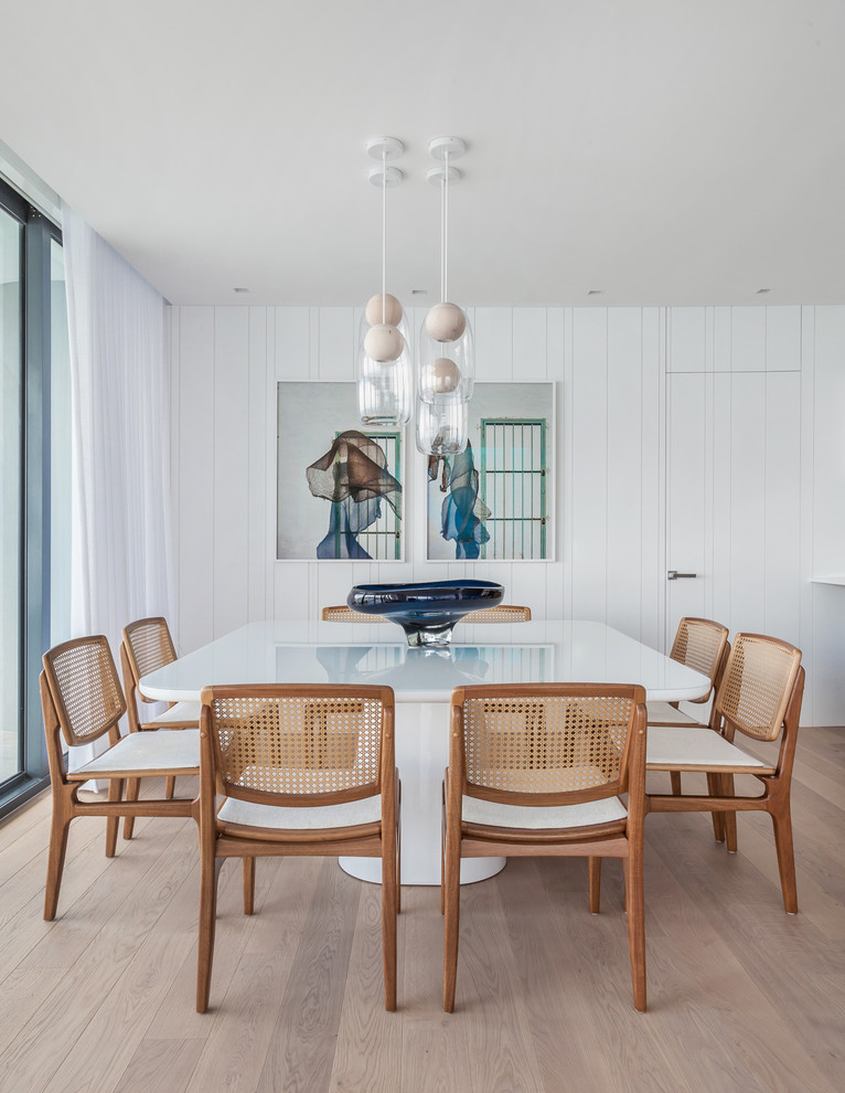Photo of a beach style dining room in Miami with white walls, light hardwood floors and no fireplace.