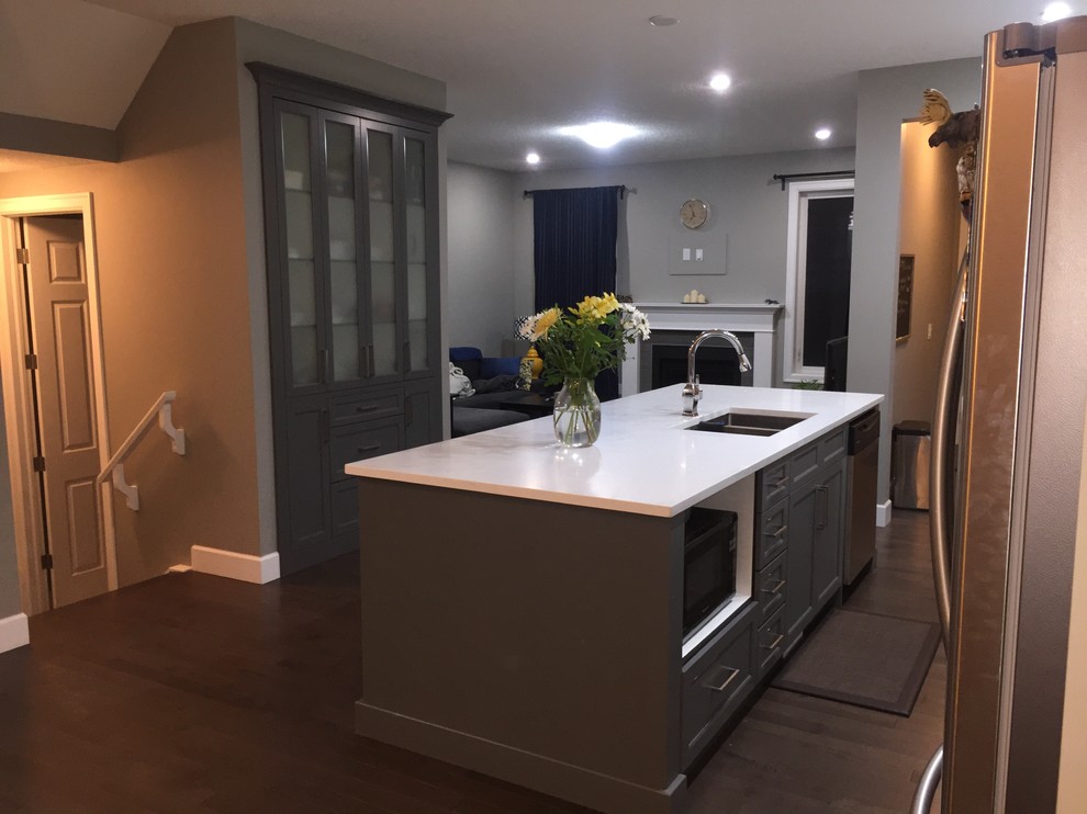 Mid-sized single-wall dark wood floor eat-in kitchen photo in Calgary with an undermount sink, shaker cabinets, white cabinets, quartzite countertops, gray backsplash, subway tile backsplash, stainless steel appliances and an island