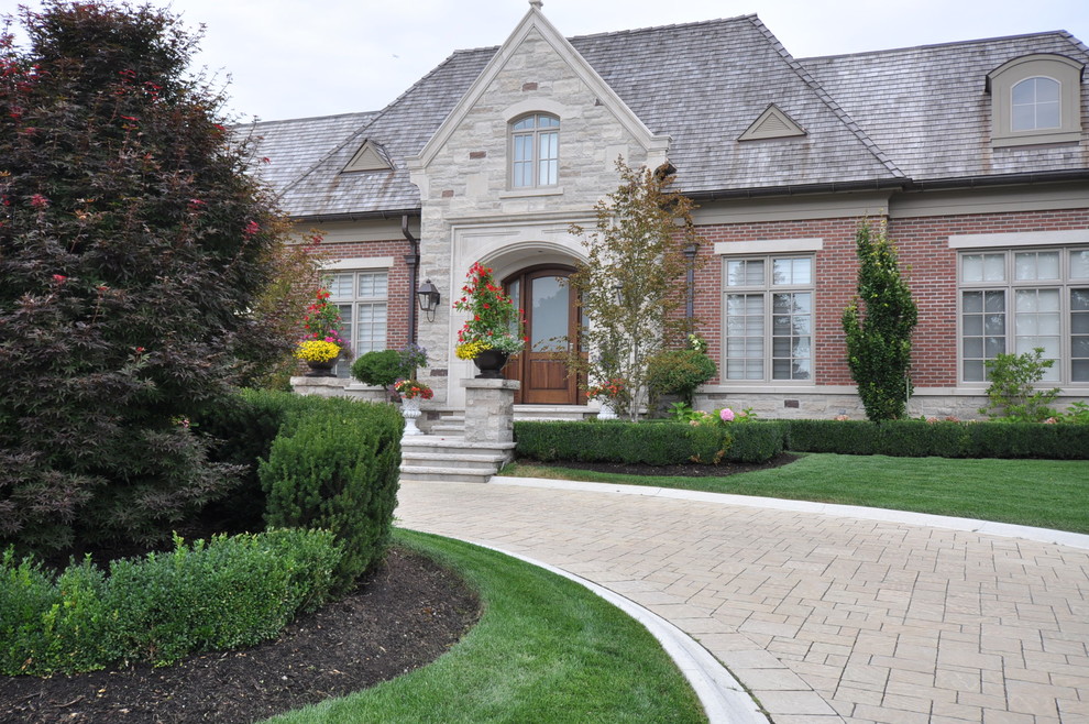 Photo of a large traditional front yard full sun driveway in Toronto with brick pavers and a garden path.