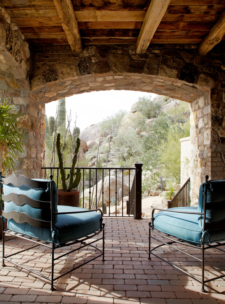 Small mediterranean verandah in Phoenix with brick pavers and a roof extension.