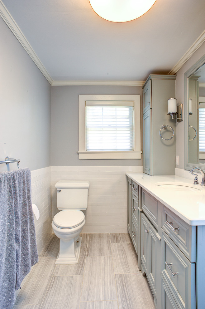 This is an example of a mid-sized transitional 3/4 bathroom in Philadelphia with a two-piece toilet, grey walls, porcelain floors, an undermount sink, grey floor, recessed-panel cabinets, grey cabinets, white tile, subway tile and solid surface benchtops.