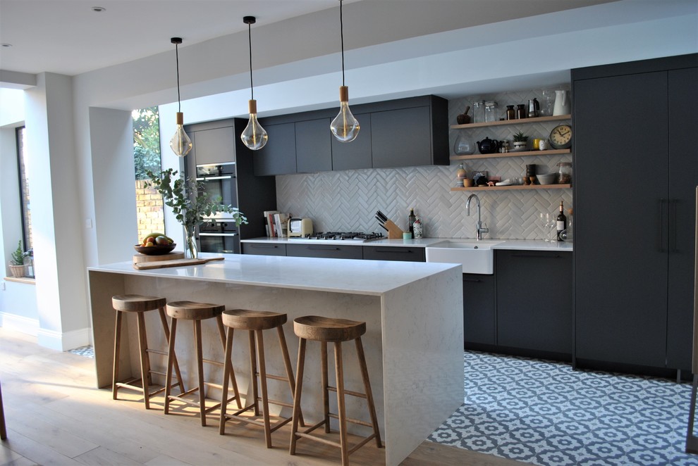 Inspiration for a contemporary eat-in kitchen in London with a farmhouse sink, flat-panel cabinets, grey cabinets, quartzite benchtops, white splashback, subway tile splashback, ceramic floors and multi-coloured floor.