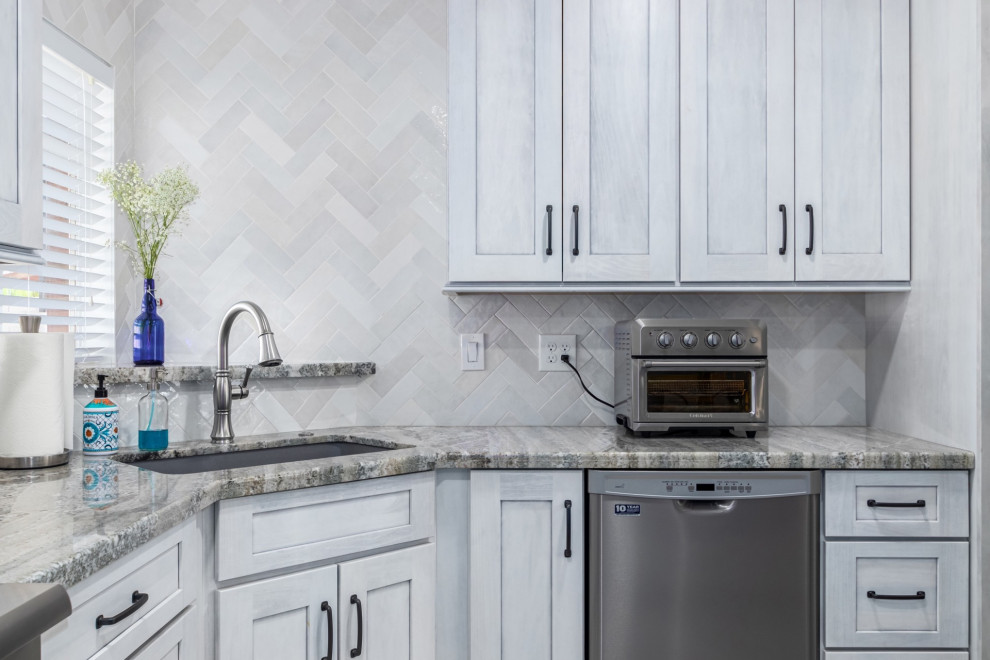 Kitchen - transitional l-shaped kitchen idea in Phoenix with a single-bowl sink, shaker cabinets, white cabinets, granite countertops, white backsplash and stainless steel appliances