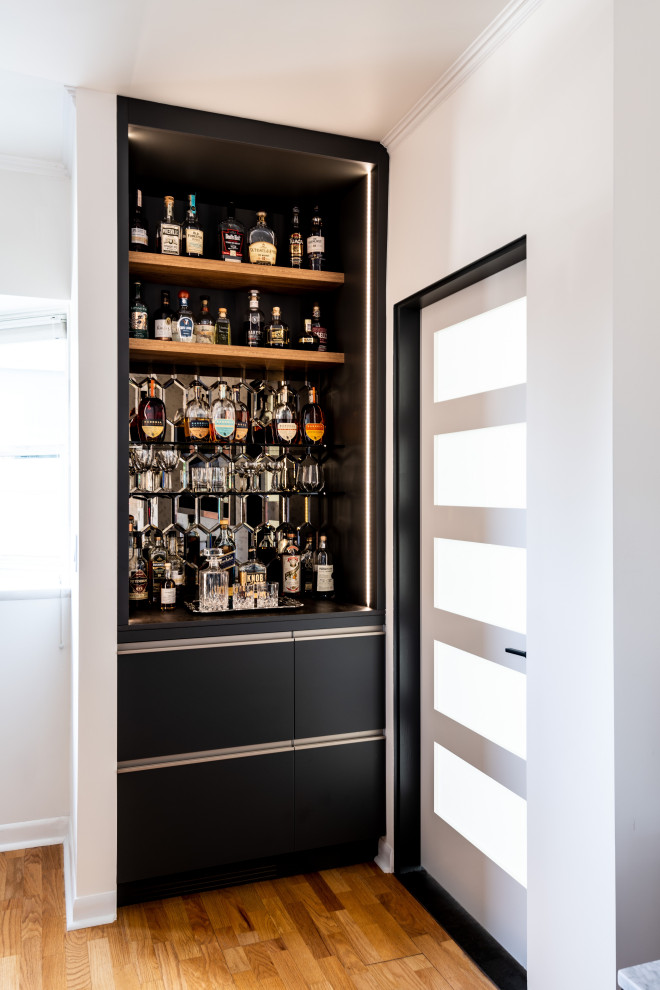 Esempio di un piccolo angolo bar senza lavandino moderno con ante lisce, paraspruzzi a specchio e ante nere