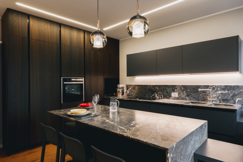 Photo of a mid-sized contemporary u-shaped open plan kitchen in Milan with a double-bowl sink, flat-panel cabinets, grey cabinets, marble benchtops, grey splashback, marble splashback, panelled appliances, painted wood floors, with island, brown floor, grey benchtop and recessed.