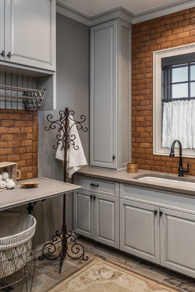 Inspiration for a rustic dedicated laundry room remodel with an undermount sink, raised-panel cabinets, gray cabinets, gray walls and gray countertops