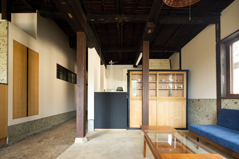 This is an example of an asian living room in Other with white walls, concrete floors and grey floor.