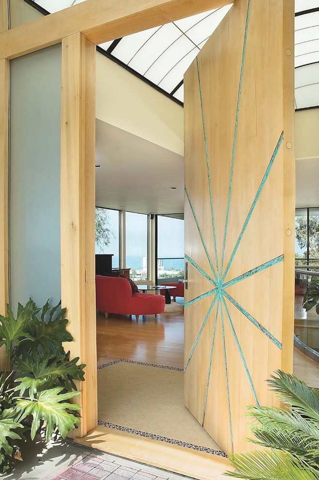 This is an example of a contemporary entryway in San Diego with a pivot front door and a light wood front door.