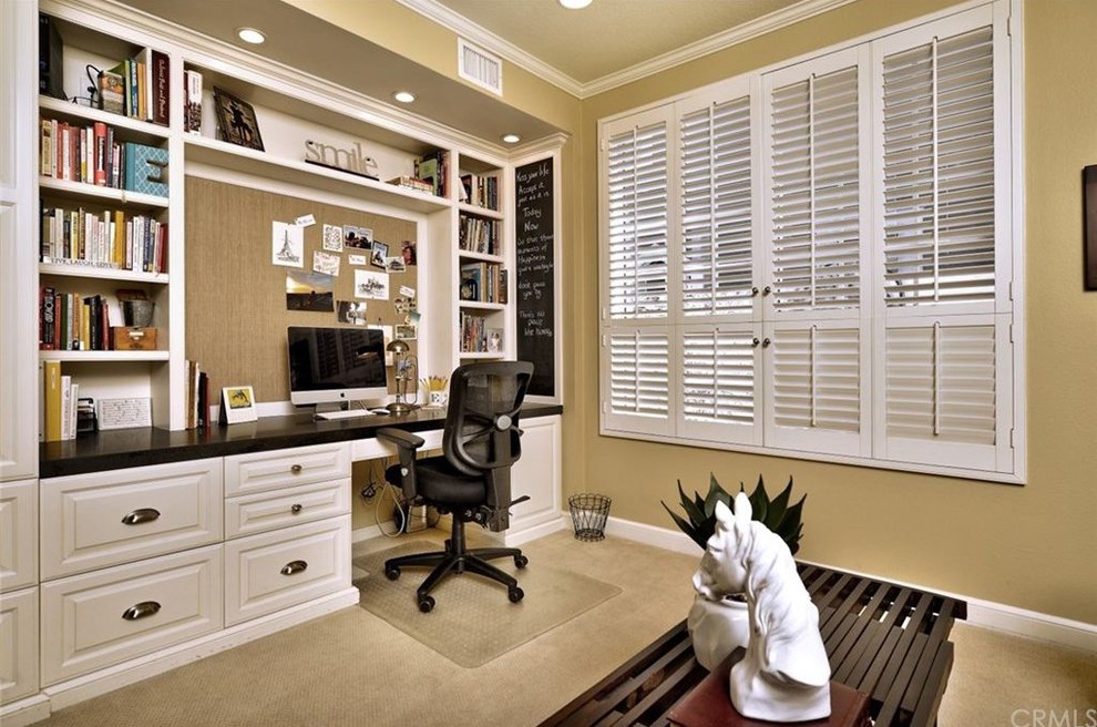 This is an example of a small transitional study room in Orange County with beige walls, carpet, no fireplace, a built-in desk and beige floor.