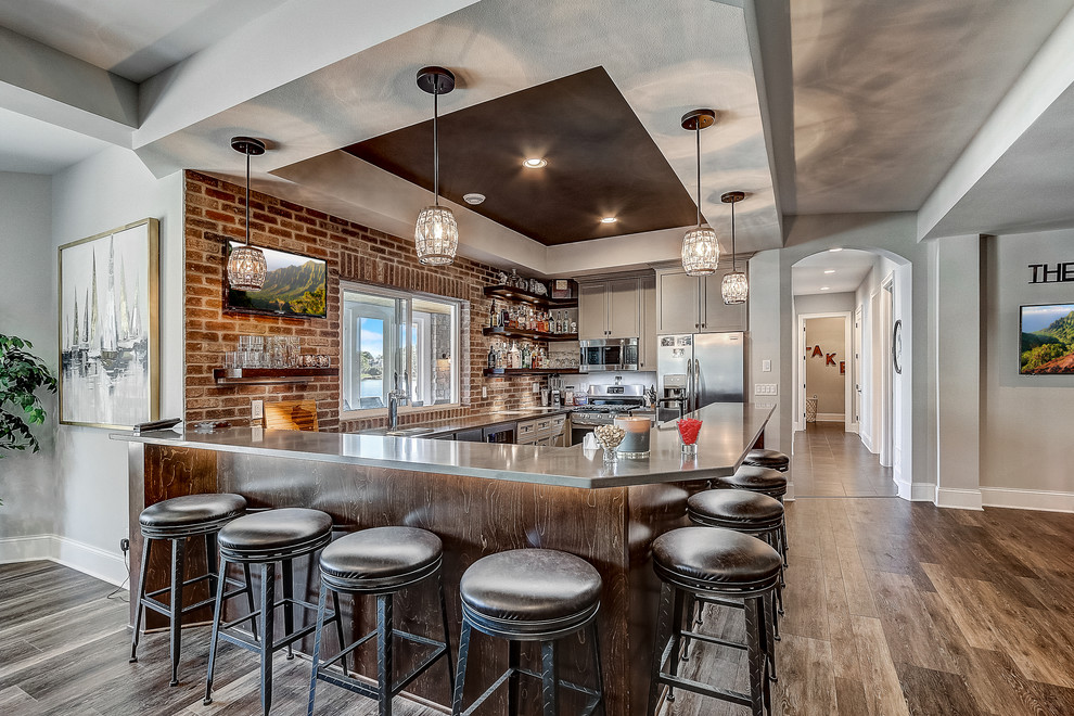 Inspiration for an expansive beach style l-shaped seated home bar in Milwaukee with an undermount sink, flat-panel cabinets, grey cabinets, quartz benchtops, brown splashback, brick splashback, multi-coloured floor and grey benchtop.