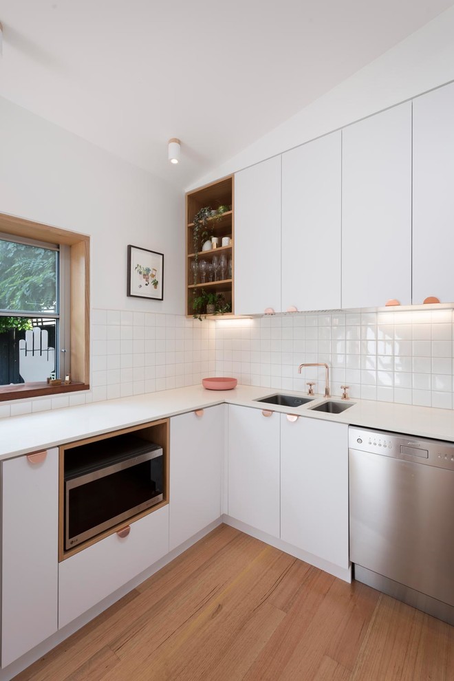 Photo of a small scandinavian kitchen in Melbourne with white cabinets, terrazzo benchtops, white splashback, ceramic splashback, light hardwood floors and white benchtop.