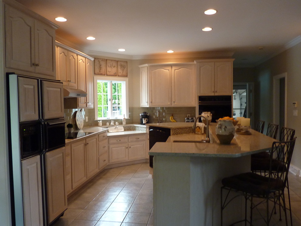 Inspiration for a large transitional l-shaped ceramic tile eat-in kitchen remodel with an undermount sink, raised-panel cabinets, light wood cabinets, quartzite countertops, beige backsplash, glass tile backsplash, stainless steel appliances and an island