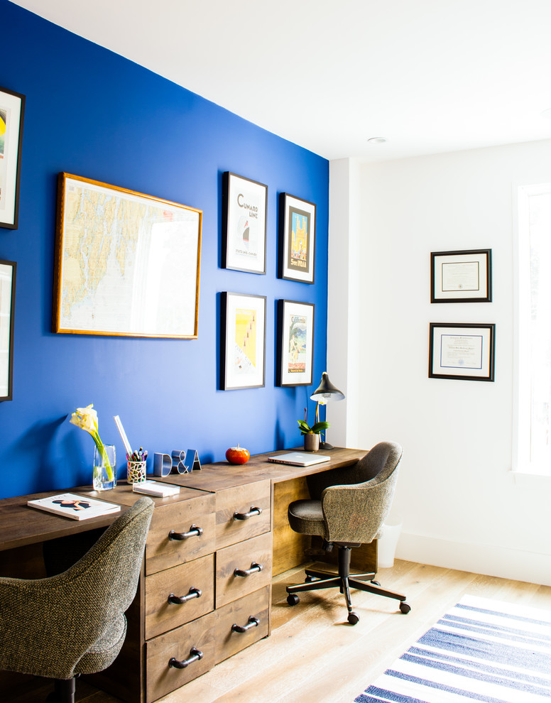 This is an example of a mid-sized transitional study room in Los Angeles with blue walls, light hardwood floors and a freestanding desk.