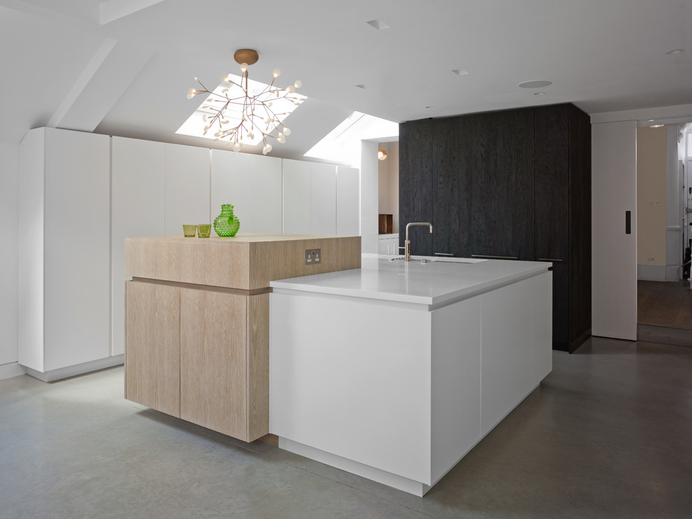 Photo of a mid-sized contemporary galley eat-in kitchen in London with flat-panel cabinets, white cabinets, white splashback, panelled appliances, concrete floors, with island, grey floor, an undermount sink and yellow benchtop.