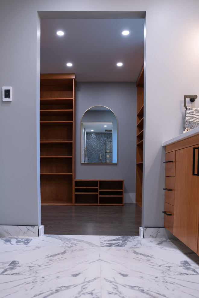 Trendy gender-neutral laminate floor and brown floor walk-in closet photo in Ottawa with flat-panel cabinets and medium tone wood cabinets