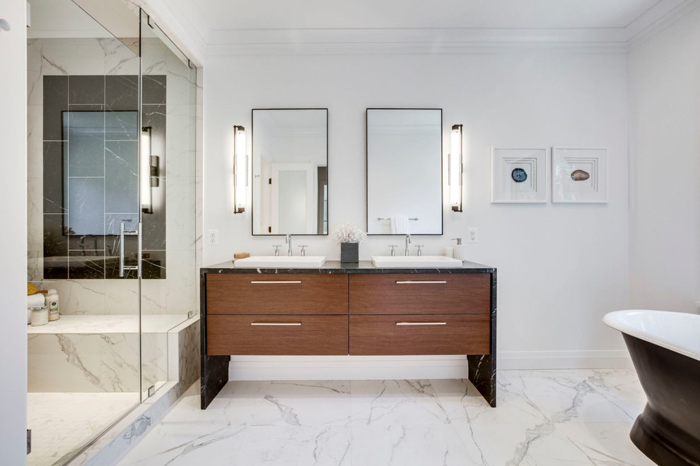 This is an example of a transitional master bathroom in DC Metro with flat-panel cabinets, dark wood cabinets, a freestanding tub, an alcove shower, black tile, black and white tile, multi-coloured tile, white tile, marble, white walls, marble floors, white floor, a hinged shower door and black benchtops.
