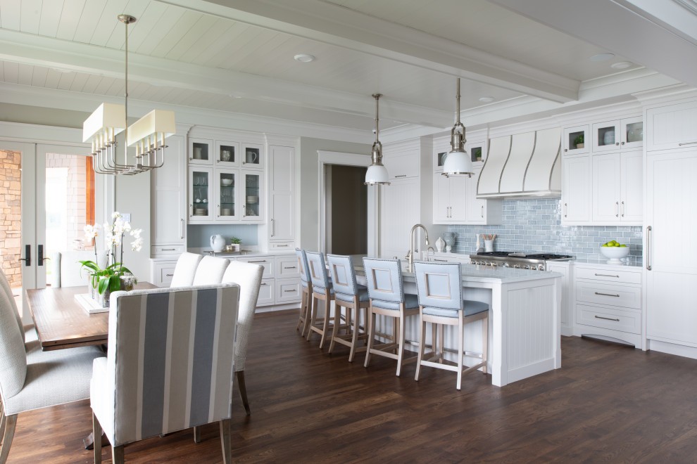 Inspiration for a large beach style l-shaped open plan kitchen in Minneapolis with a farmhouse sink, flat-panel cabinets, quartzite benchtops, blue splashback, subway tile splashback, panelled appliances, medium hardwood floors, with island, brown floor, white benchtop and timber.