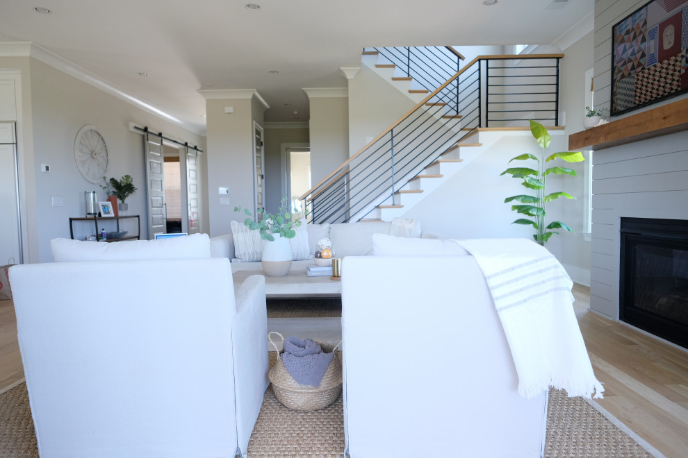 This is an example of a mid-sized beach style open concept living room in Charleston with grey walls, medium hardwood floors, a standard fireplace and a wall-mounted tv.