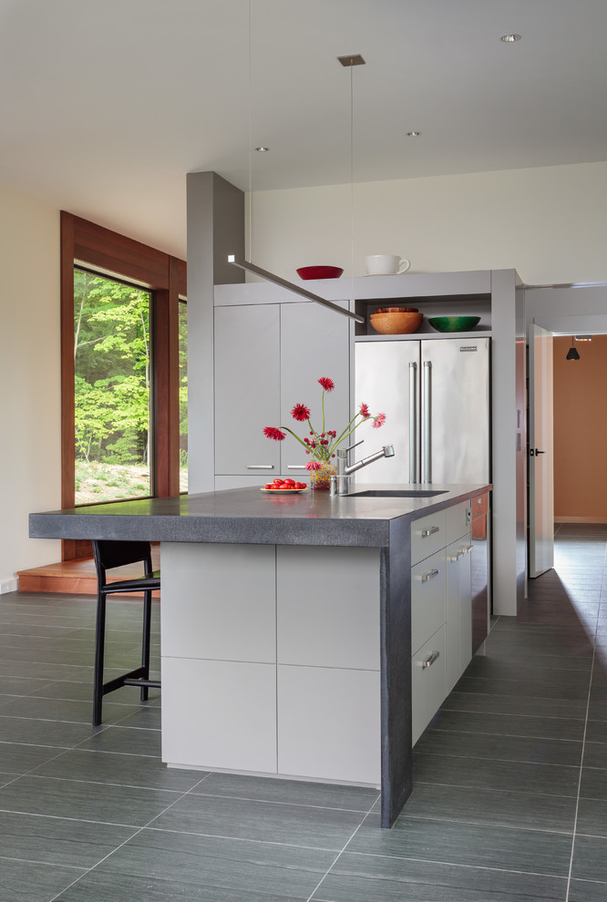 Mid-sized contemporary l-shaped kitchen in New York with a single-bowl sink, flat-panel cabinets, granite benchtops, stainless steel appliances, limestone floors, with island and white cabinets.