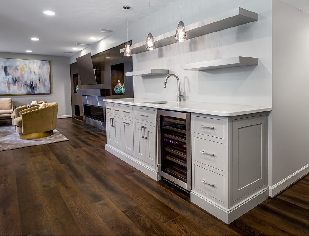 Inspiration for a small transitional single-wall wet bar in DC Metro with an undermount sink, shaker cabinets, white cabinets, quartz benchtops, dark hardwood floors, brown floor and white benchtop.