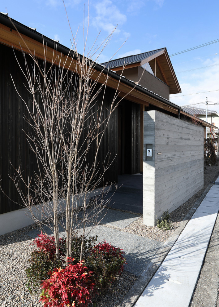 Diseño de puerta principal de estilo zen grande con paredes marrones, suelo de granito, puerta simple, puerta de madera oscura, suelo gris y madera