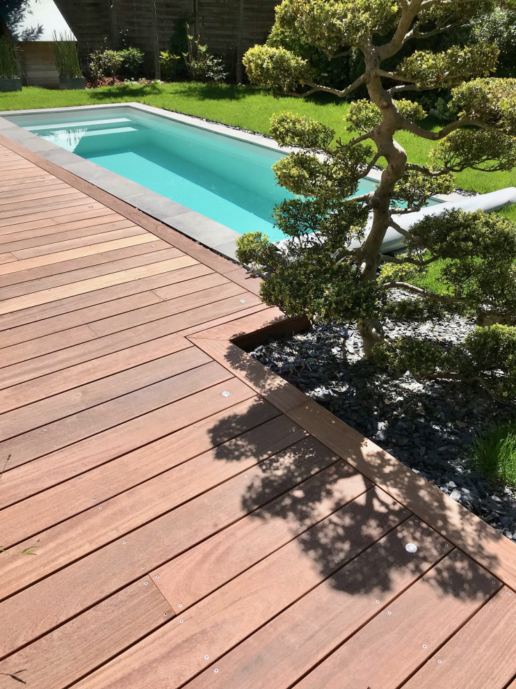 Aménagement d'un piscine avec aménagement paysager avant moderne de taille moyenne et rectangle avec une terrasse en bois.